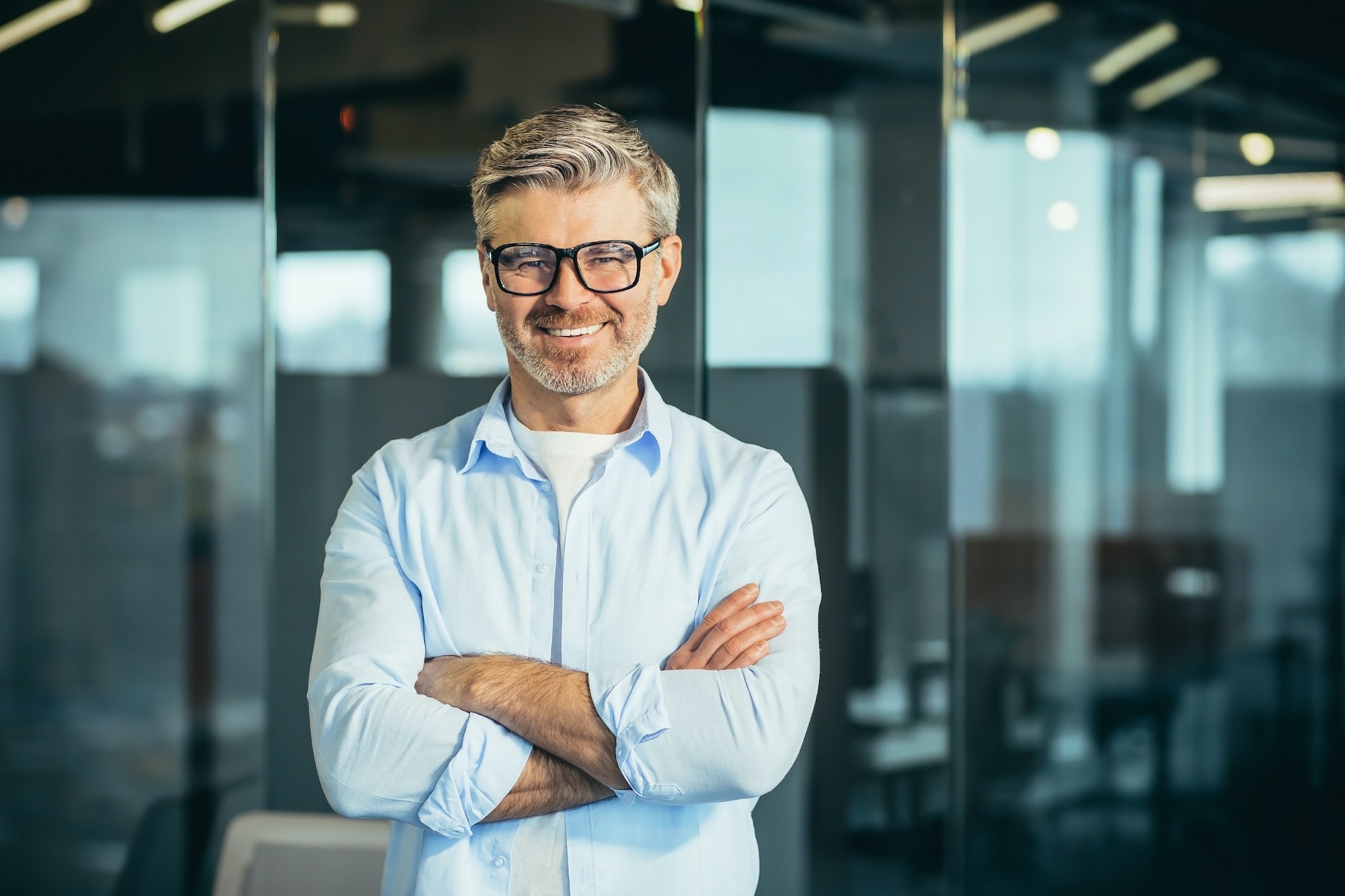 Portrait of senior and experienced male boss boss, with arms crossed, smiling and looking