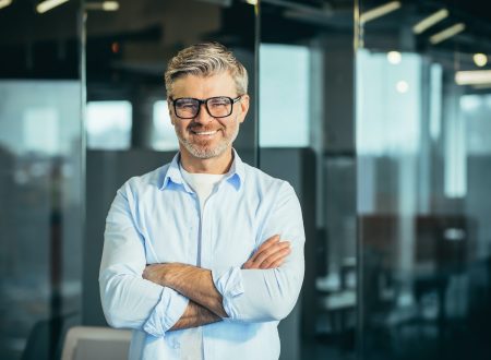 Portrait of senior and experienced male boss boss, with arms crossed, smiling and looking